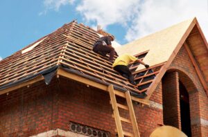 Homeowner photographs shingles and an indoor ceiling stain while organizing receipts and damage notes.
